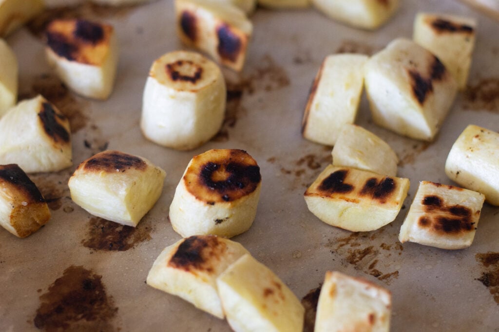 Pieces of roasted parsnip on sheet pan.