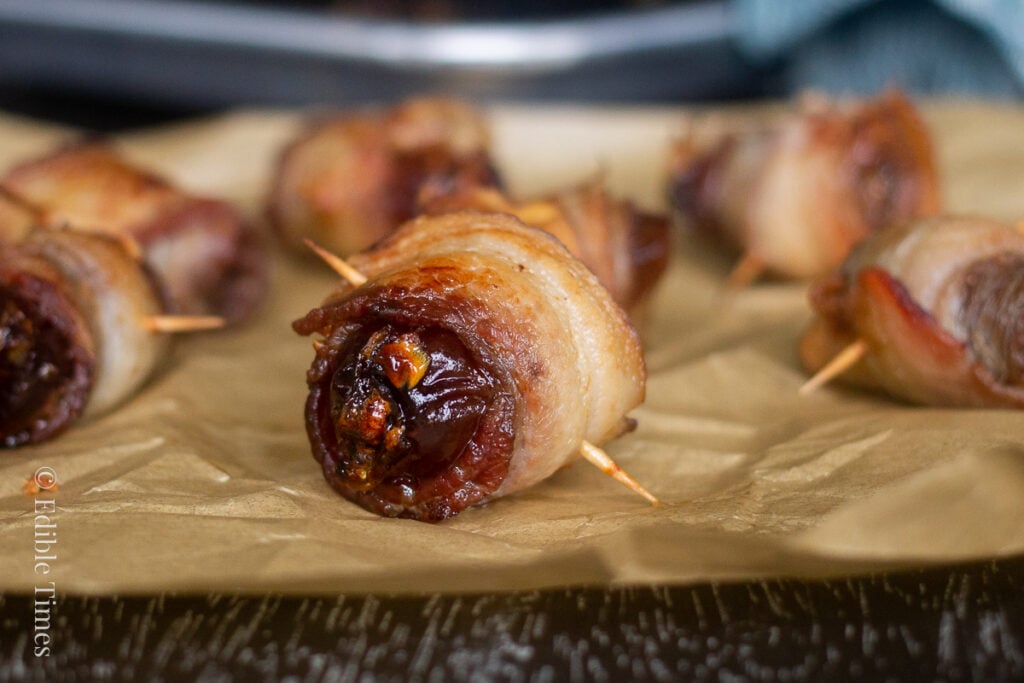 Bacon wrapped stuffed date on parchment paper.