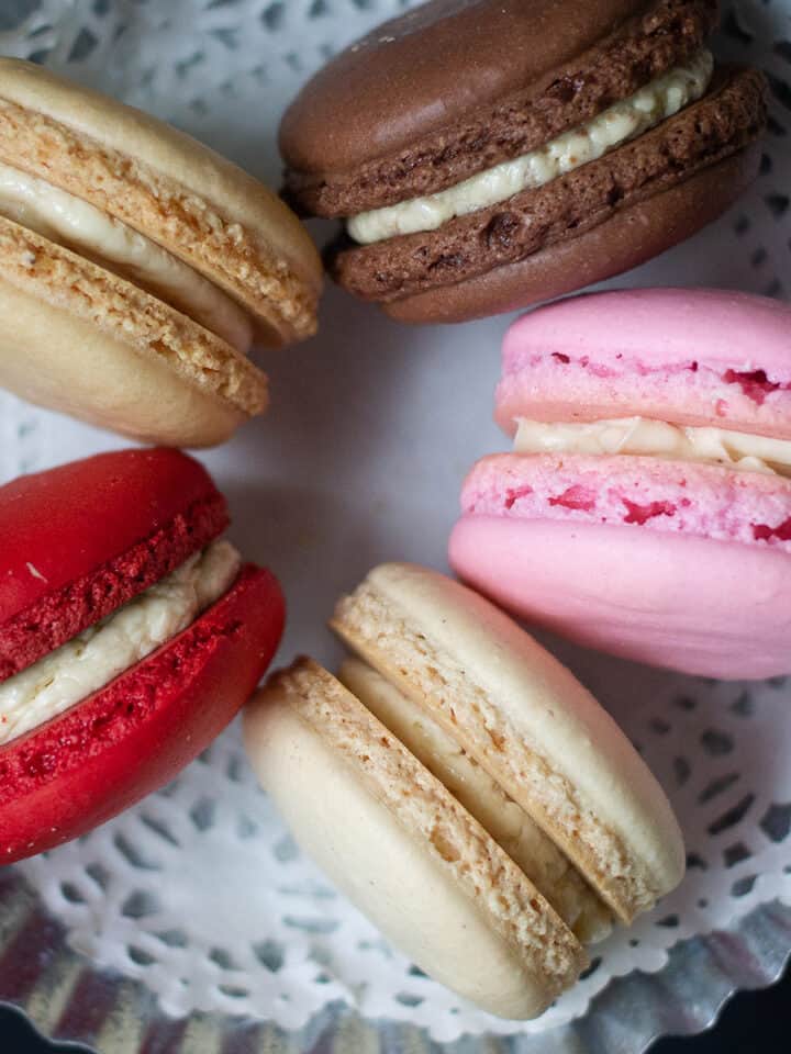 Assorted macarons of various colors and flavors on a white doily.