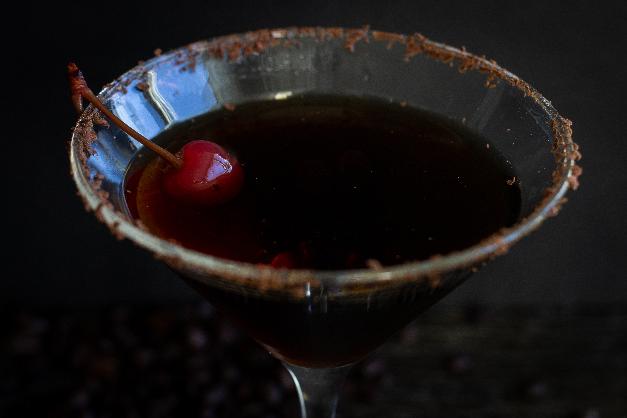 Black Russian cocktail in a martini glass garnished with a cherry.