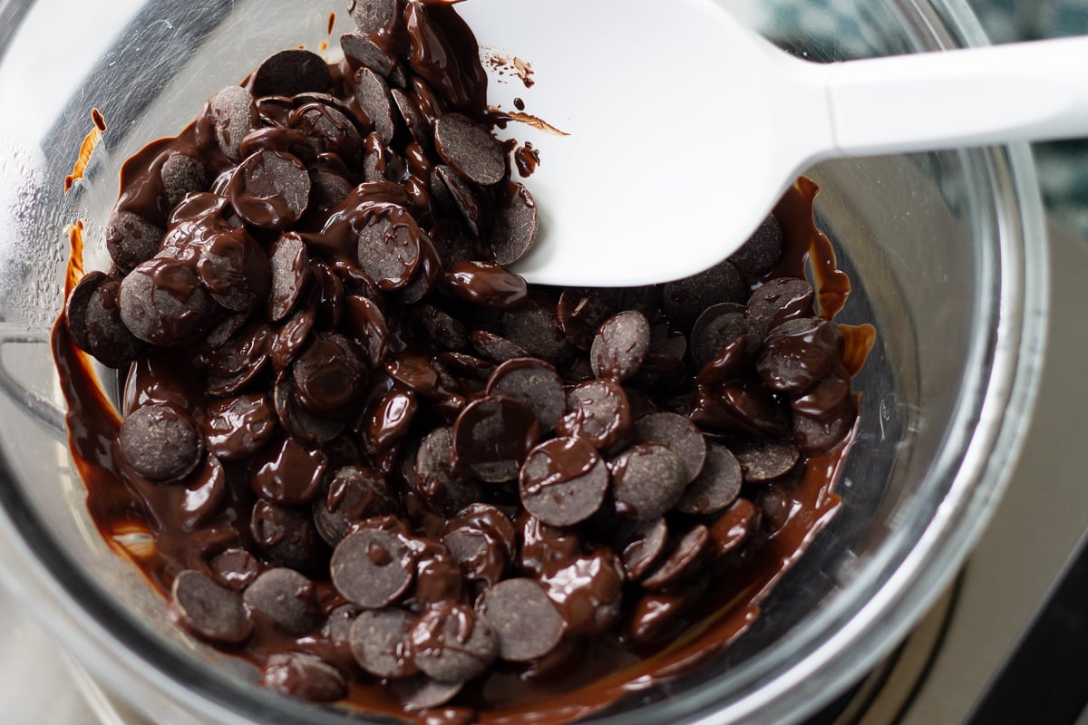 Looking down on dark chocolate chips melting in a glass bowl set over a small pot of simmering water.