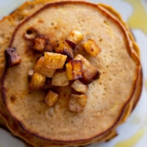 Looking down at a stack of apple pancakes with caramelized apples on top.