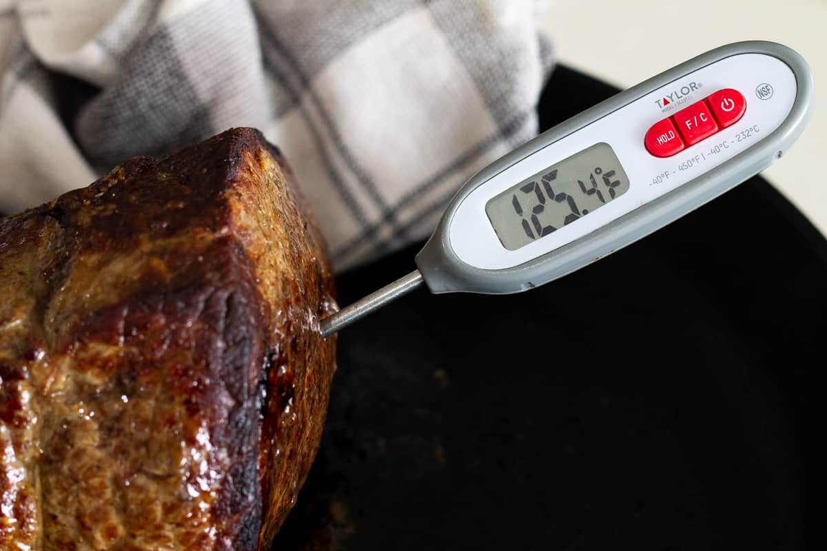 A probe thermometer inserted into a beef top (inside) round roast.