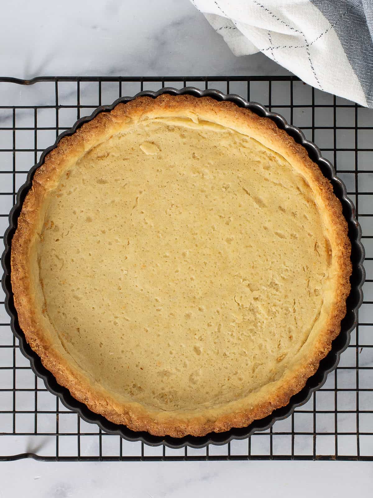 Baked tart shell on in the pan on a cooling rack.