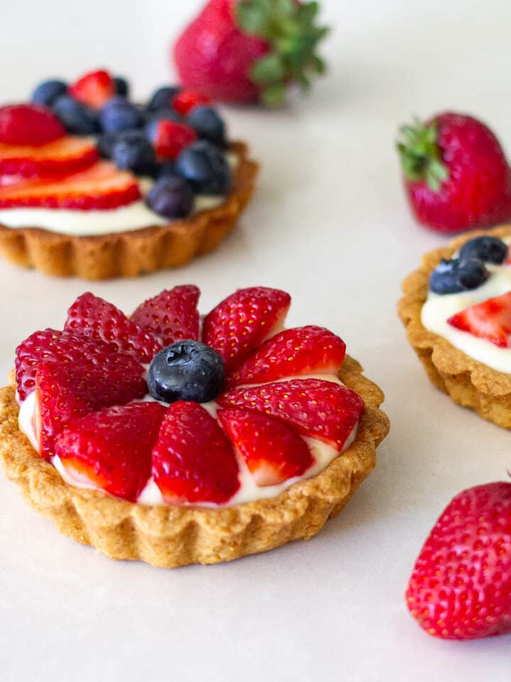 Fruit tarts on a counter filled with pastry cream.