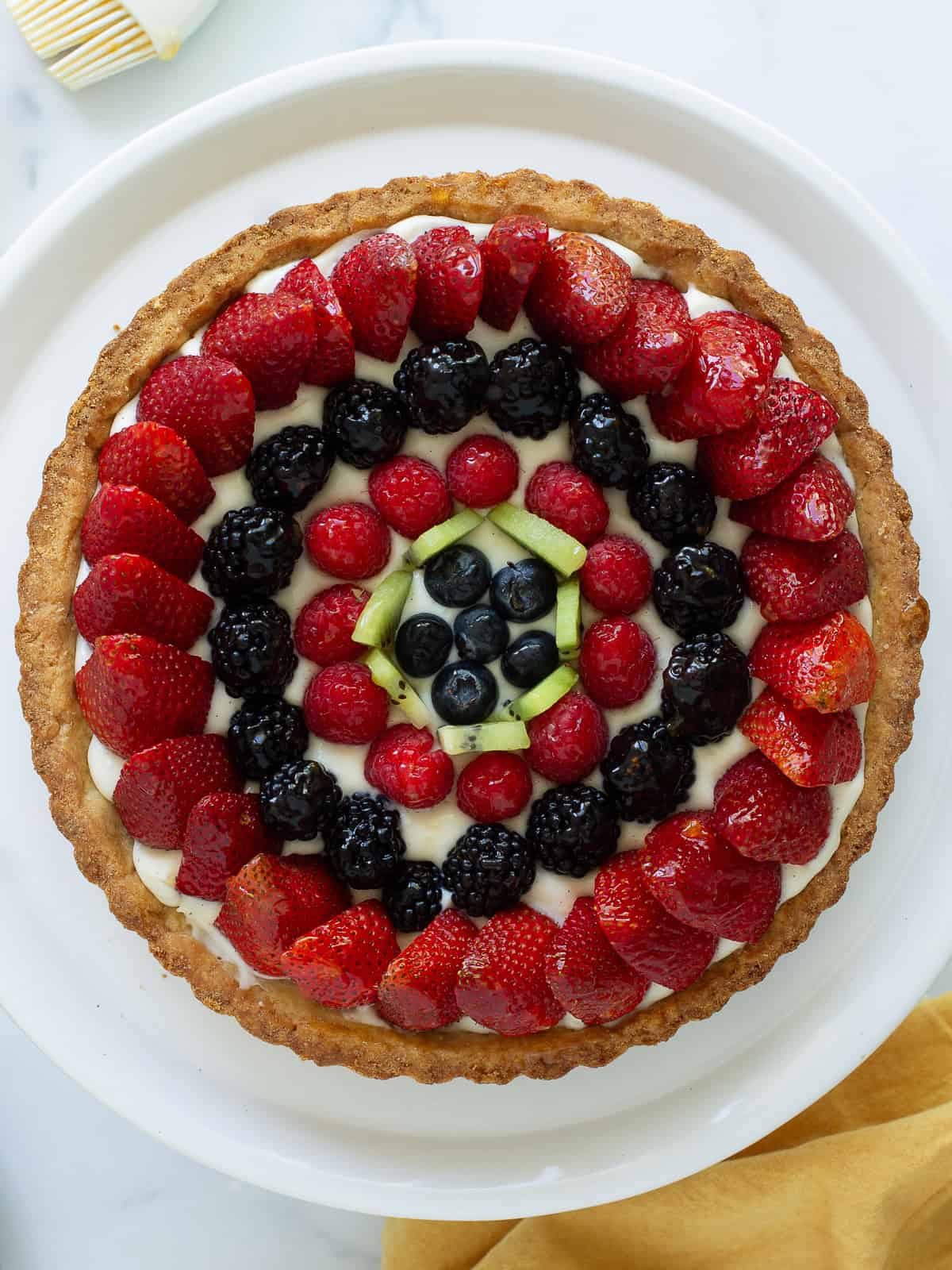 A close up look at a fresh fruit tart decorated with berries and a few kiwi slices.