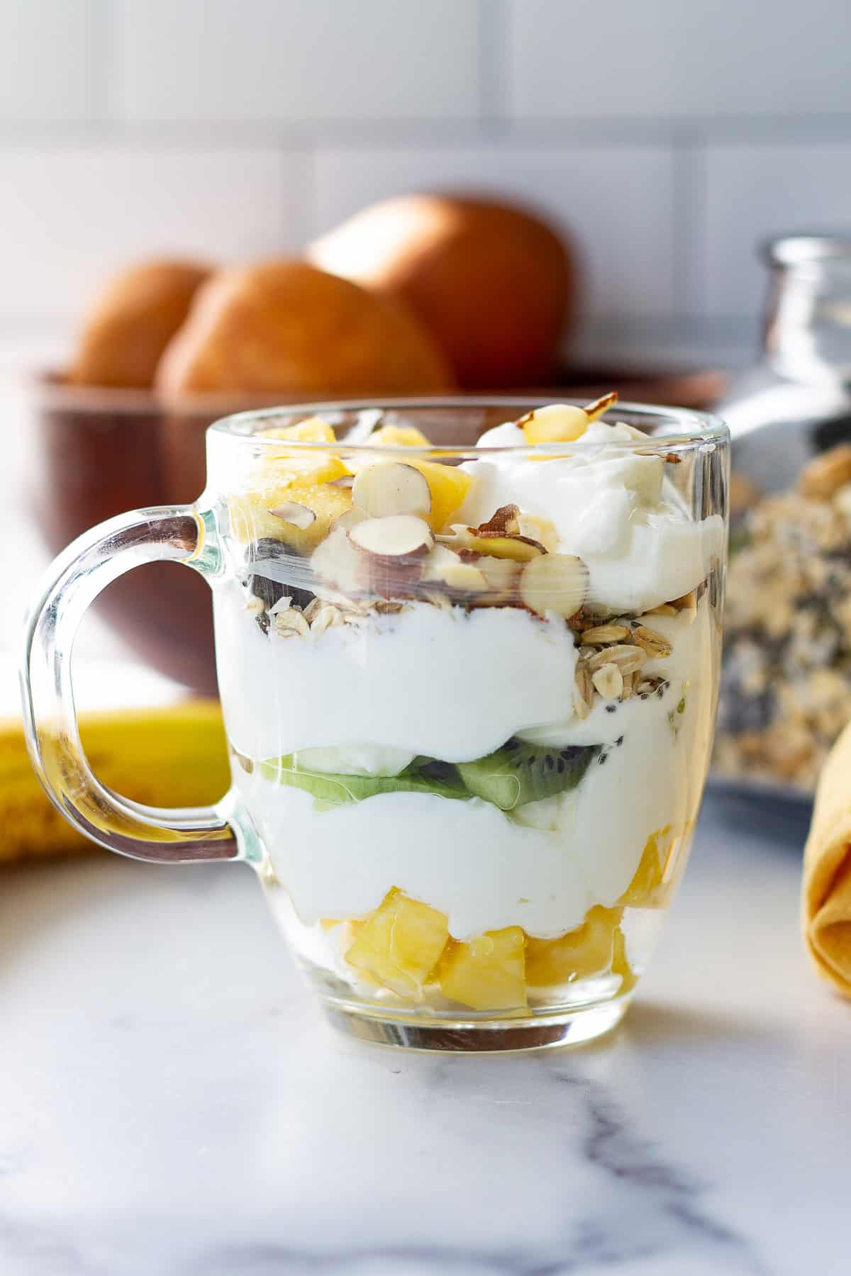 An anti-inflammatory breakfast of plain Greek yogurt topped with a rainbow of fruit, a sprinkle of muesli and almonds.