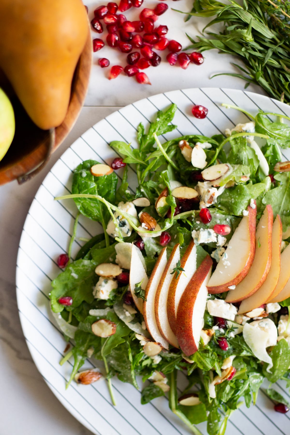 A plate of anti-inflammatory foods: pear salad with mixed greens, almonds, and pomegranate seeds.