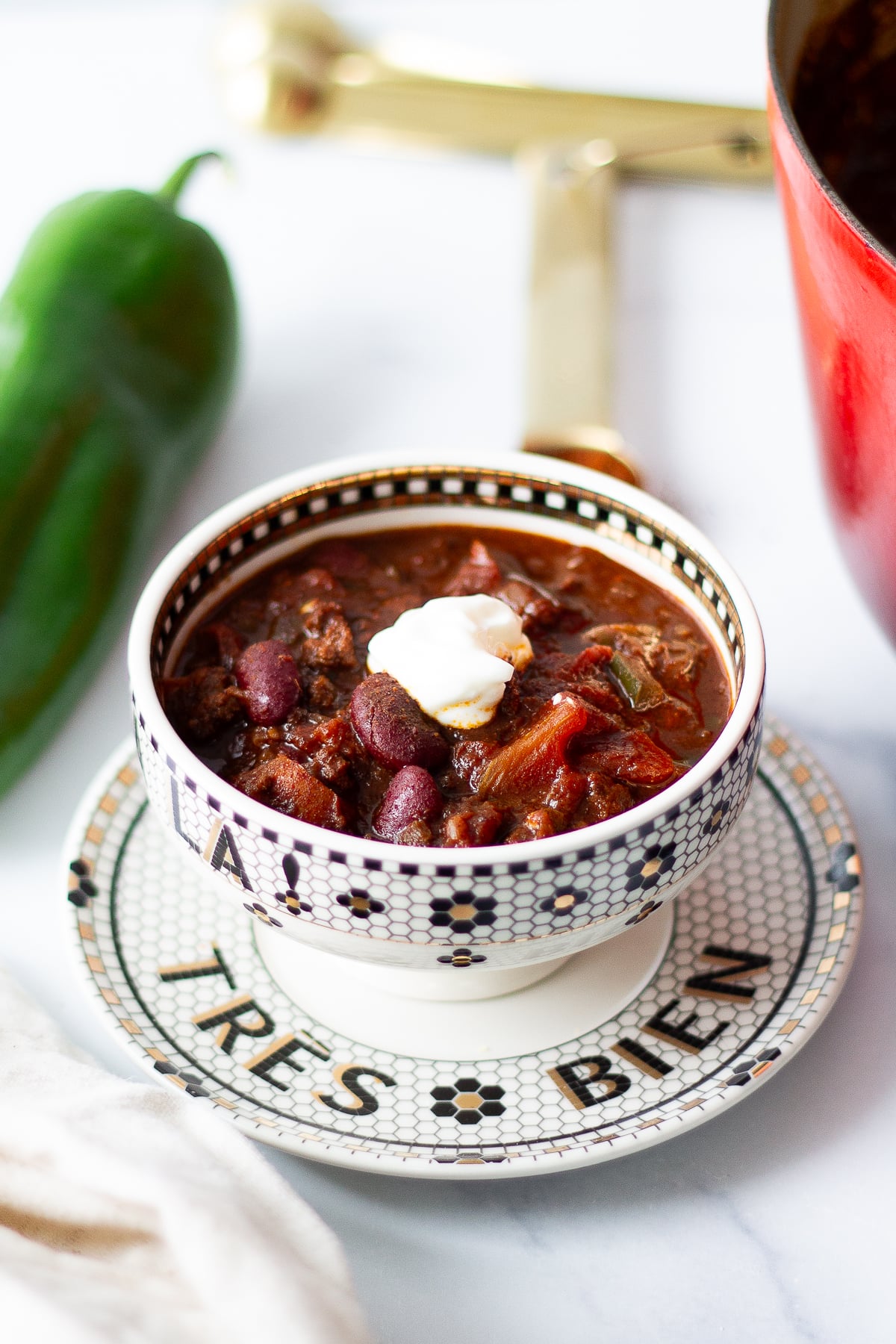 Three-pepper bean chili in a small bowl next to an anaheim pepper.