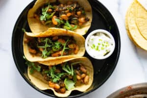Bean tacos on corn tortillas with arugula and chive sour cream.