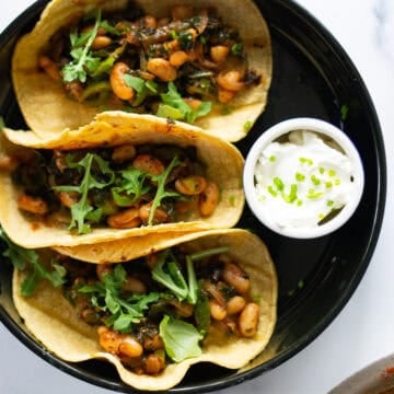 Bean tacos on corn tortillas with arugula and chive sour cream.